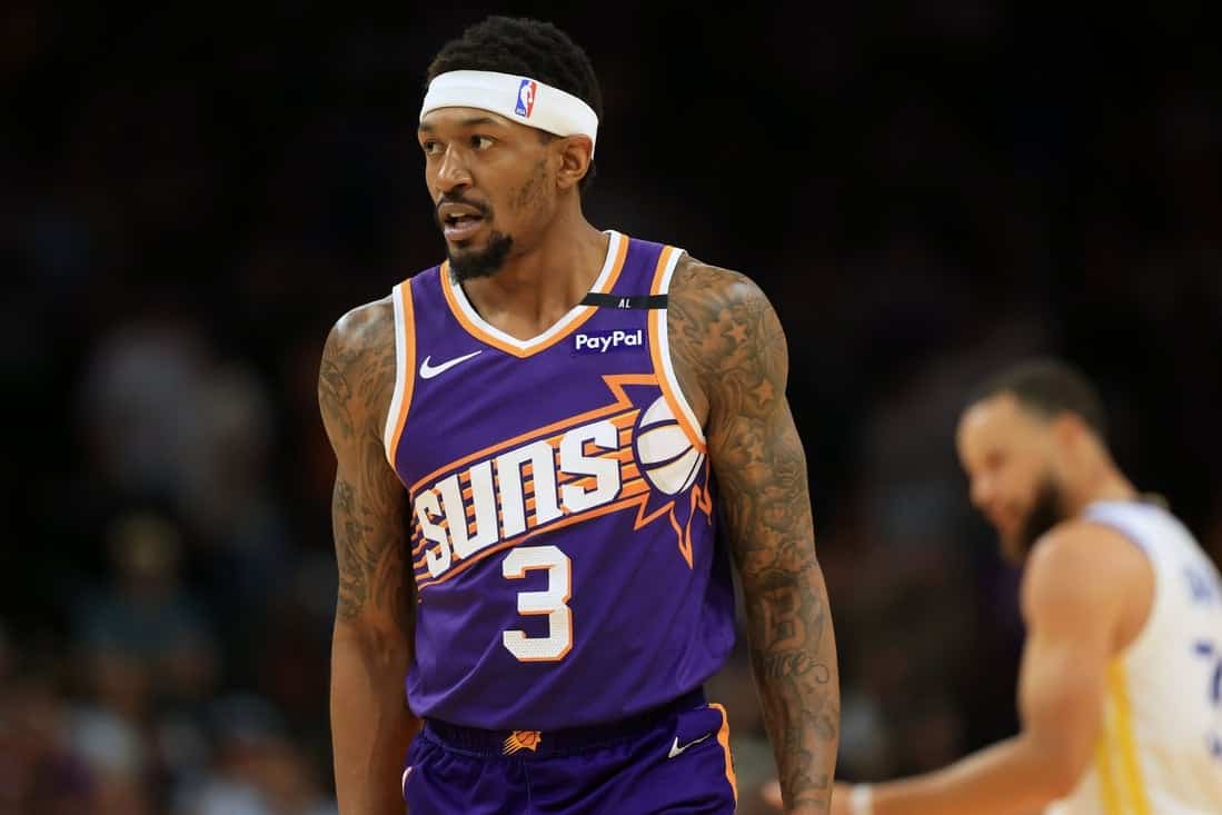 10 A basketball player in a purple Phoenix Suns jersey with the number 3 stands focused on the court during a game.