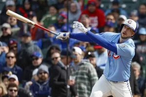 A baseball player in a light blue jersey swings a bat during a game.