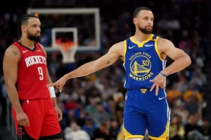 A Golden State Warriors player gestures while interacting with an opponent in a heated basketball game, showcasing competitive tension.