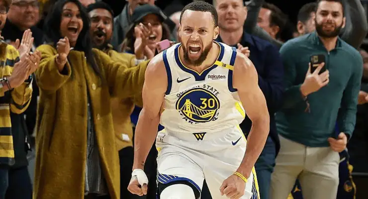  Golden State Warriors star Stephen Curry (#30) in a white jersey passionately shouting with fists clenched, as excited fans cheer in the background.