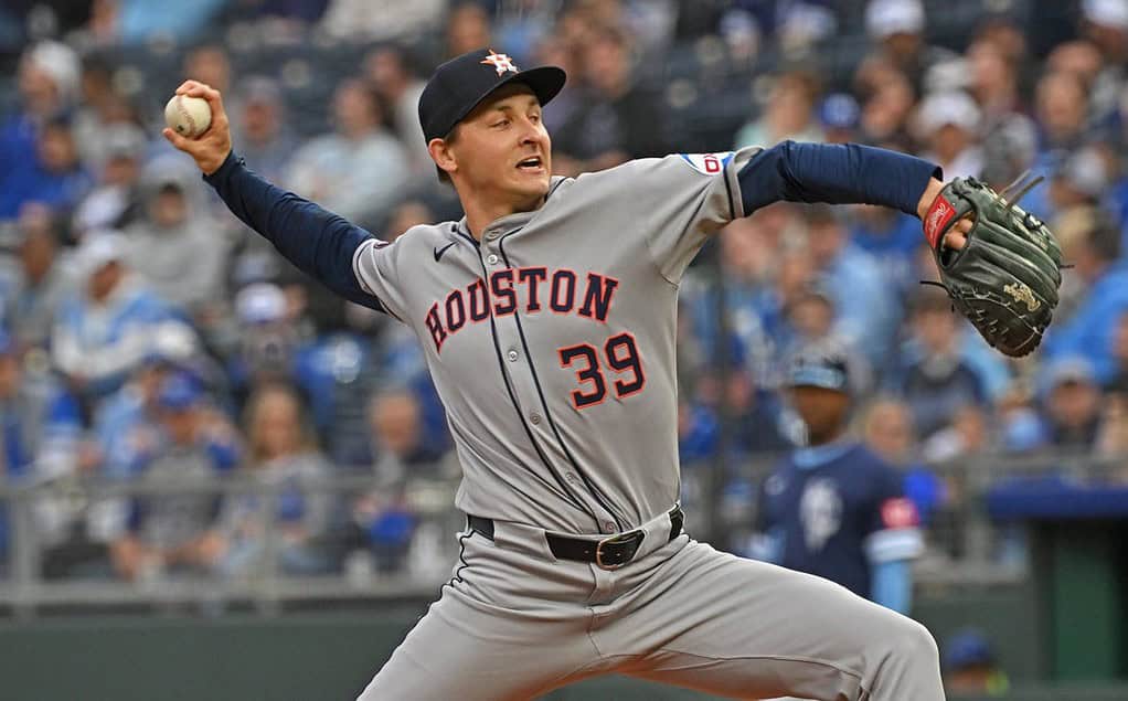 A Houston baseball player in a gray jersey, number 39, winds up to pitch on a field packed with fans in the background.