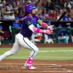 A baseball player in a vibrant purple uniform swings a bat, showcasing dynamic movement and athleticism on the field.