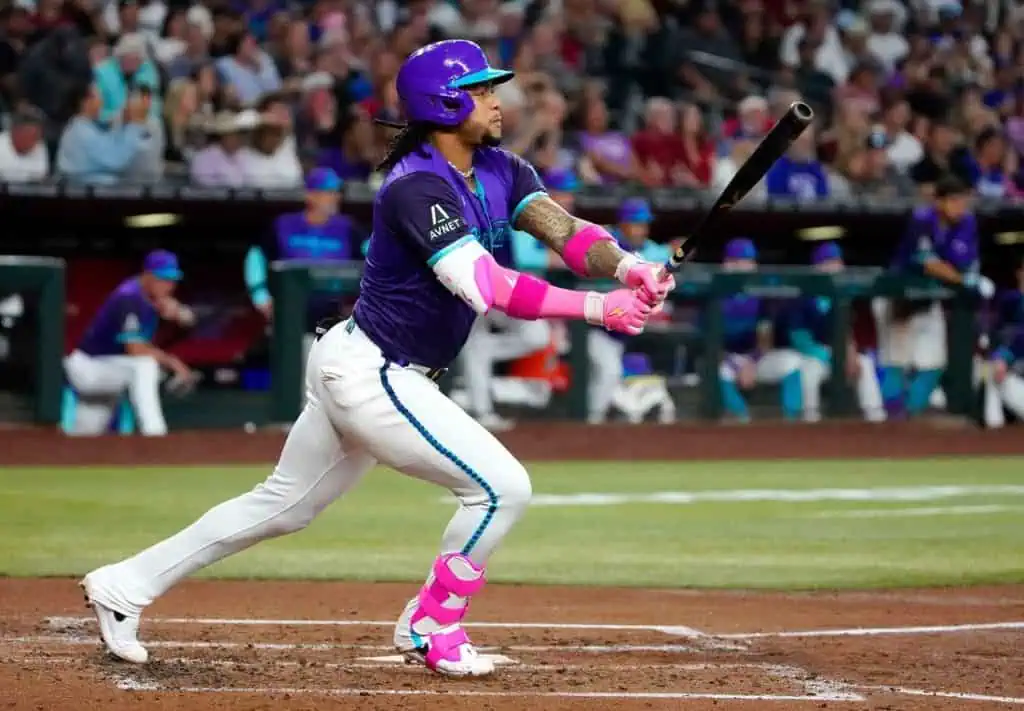 A baseball player in a vibrant purple uniform swings a bat, showcasing dynamic movement and athleticism on the field.