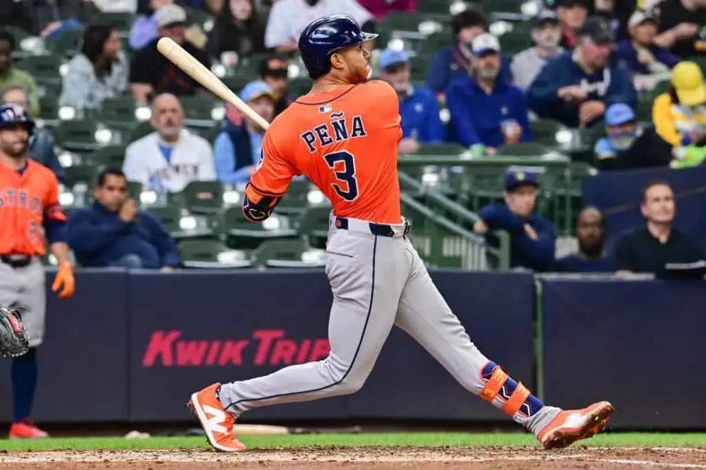 A baseball player in an orange jersey swings a bat during a game