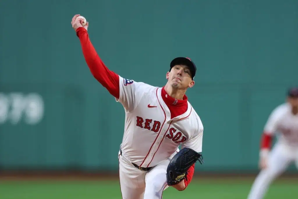 A Red Sox pitcher winds up to throw a pitch on the baseball mound, showcasing focused athleticism in a stadium setting.
