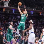 NBA game between the Boston Celtics and New York Knicks with action shot featuring a player driving to the basket during an intense matchup.
