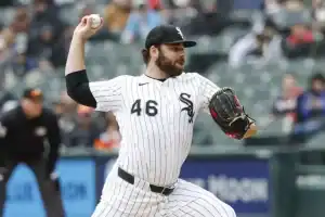 A baseball player in a white and black pinstriped uniform prepares to pitch on