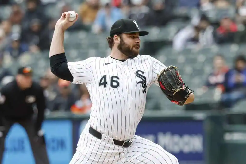 A baseball player in a white and black pinstriped uniform prepares to pitch on