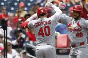 A St. Louis Cardinals player celebrates with teammates after a successful play, wearing a gray jersey with "CONTRERAS" and number 40.