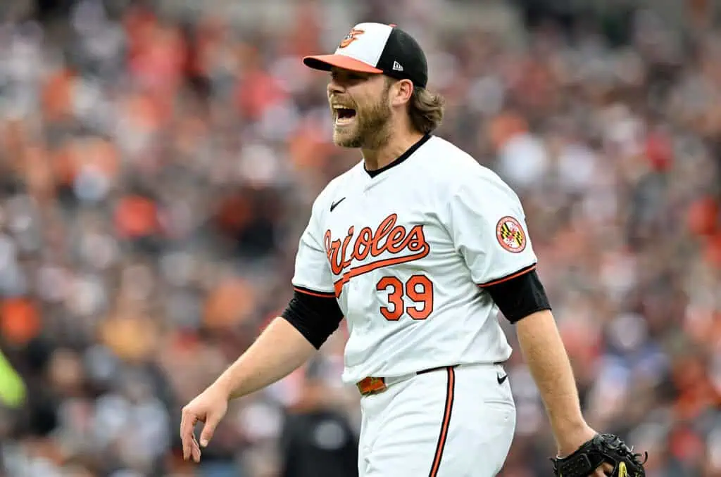 Arizona Diamondbacks vs Colorado Rockies Picks and Predictions May 16th 2025 2 A baseball player in a white and orange Orioles uniform walks on the field, focused amidst a blurred crowd in the background.