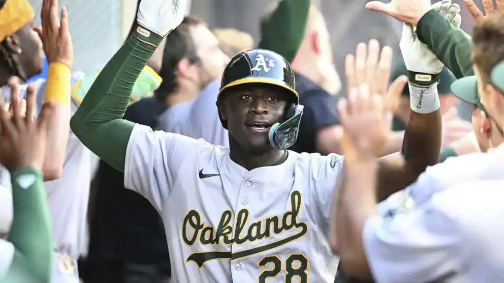Milwaukee Brewers vs Boston Red Sox Picks and Predictions May 27th 2025 3 A baseball player wearing an Oakland Athletics uniform celebrates with teammates in a lively dugout atmosphere.