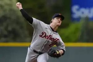 A Detroit baseball player in a gray uniform winds up to pitch on a field, showcasing focus and athleticism.