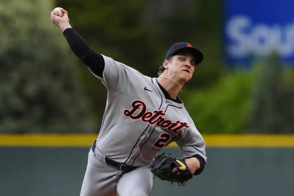 A Detroit baseball player in a gray uniform winds up to pitch on a field, showcasing focus and athleticism.