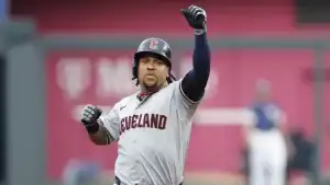 A baseball player in a gray Cleveland jersey celebrates triumphantly, raising his fist in excitement during a game.