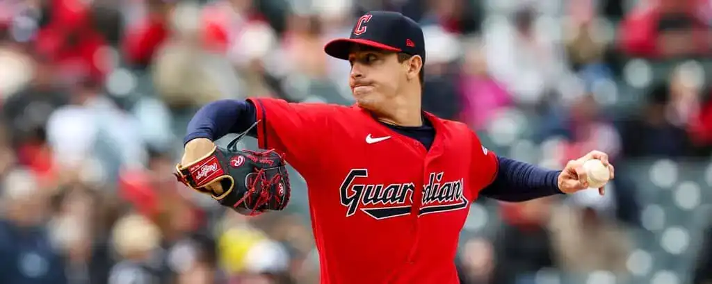 Cleveland Guardians vs Milwaukee Brewers Picks and Predictions May 13th 2025 2 A baseball player in a red Guardians jersey winds up to pitch on a sunny day at the stadium, with fans visible in the background.