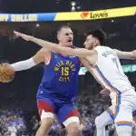 A basketball player in a blue "Mile High City" jersey faces an opponent in an Oklahoma City Thunder uniform, with intense defensive action.