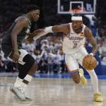 A player in an Oklahoma City Thunder uniform dribbles past an opponent in a basketball game, showcasing agility and speed.