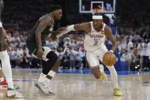 A player in an Oklahoma City Thunder uniform dribbles past an opponent in a basketball game, showcasing agility and speed.