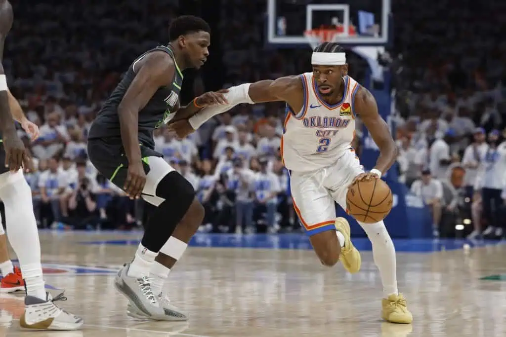 A player in an Oklahoma City Thunder uniform dribbles past an opponent in a basketball game, showcasing agility and speed.