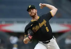 A baseball player in a black Pittsburgh Pirates jersey winds up to pitch, showcasing athletic form in a stadium setting.