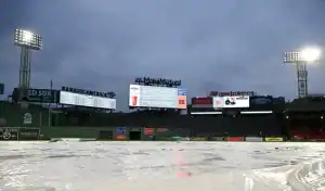 Fenway Park scoreboard and tarp-covered field during rain delay before Boston Red Sox vs Baltimore Orioles game on May 24, 2025.