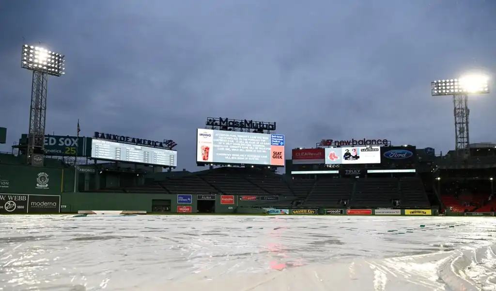 Fenway Park scoreboard and tarp-covered field during rain delay before Boston Red Sox vs Baltimore Orioles game on May 24, 2025.