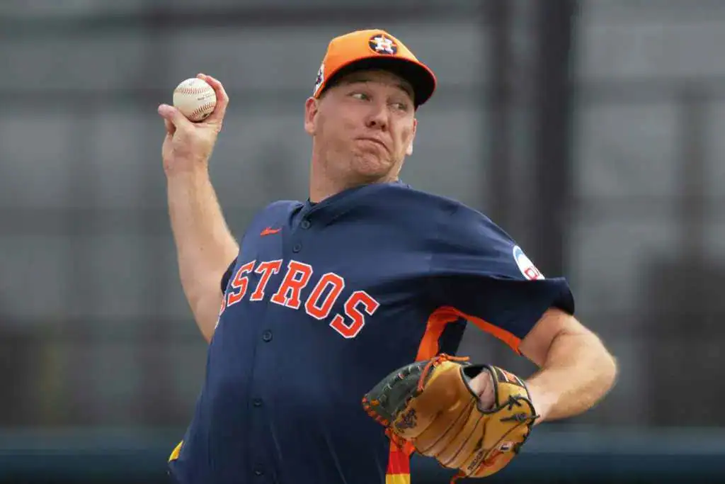 Houston Astros vs Seattle Mariners Picks and Predictions May 23rd 2025 2 A Houston Astros player in a blue jersey, wearing an orange cap, prepares to pitch a baseball on the field during practice.