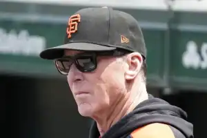 A person wearing a black San Francisco Giants cap and jacket stands outdoors, with a baseball stadium backdrop visible.