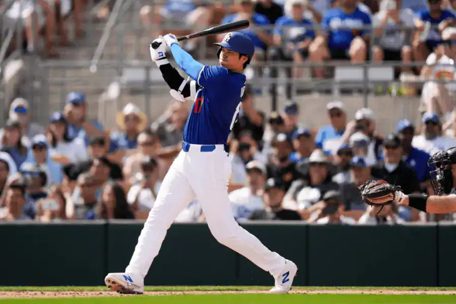 Cleveland Guardians vs Los Angeles Dodgers Picks and Predictions May 27th 2025 2 A baseball player in a blue jersey swings a bat in a sunny stadium, with a crowd of fans visible in the background.