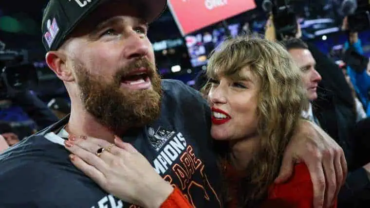 A jubilant celebration captures a person wearing a championship shirt, surrounded by cheering fans and cameras, exuding joy and excitement.