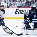 A St. Louis Blues player attempts to score against a Winnipeg Jets goalie during an intense hockey match