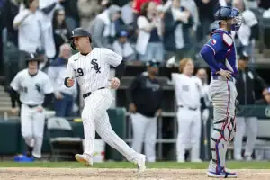 A Chicago White Sox player rounds the bases, celebrating a run, while a Texas Rangers catcher watches in disappointment, surrounded by cheering fans.