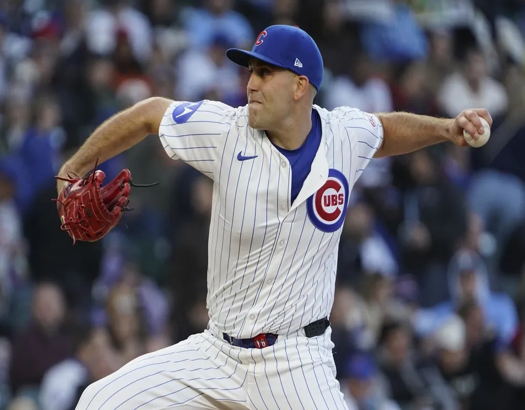 Chicago Cubs pitcher mid-delivery on the mound with a blurred crowd in the background
