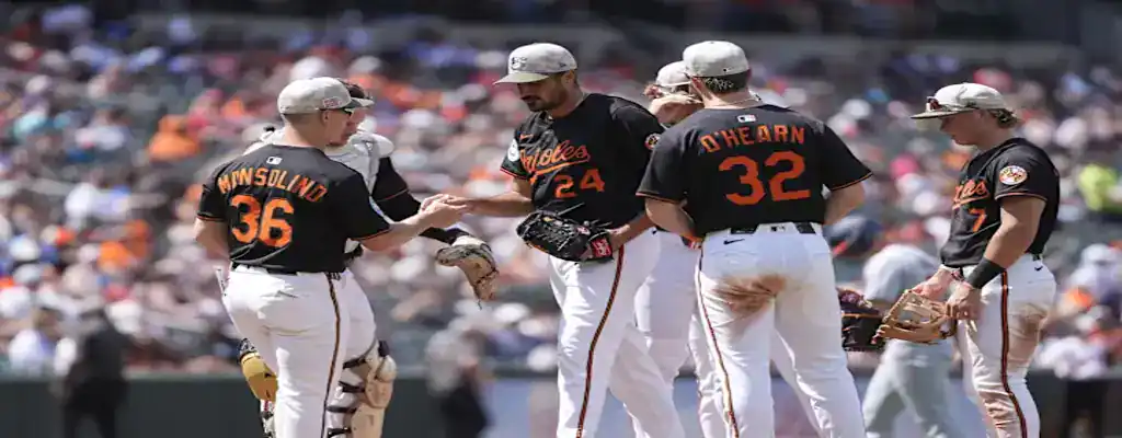 Baltimore Orioles vs Chicago White Sox Picks and Predictions May 31st 2025 3 Baltimore Orioles players gather at the pitcher's mound during a game, wearing black jerseys and gray caps under sunny skies.