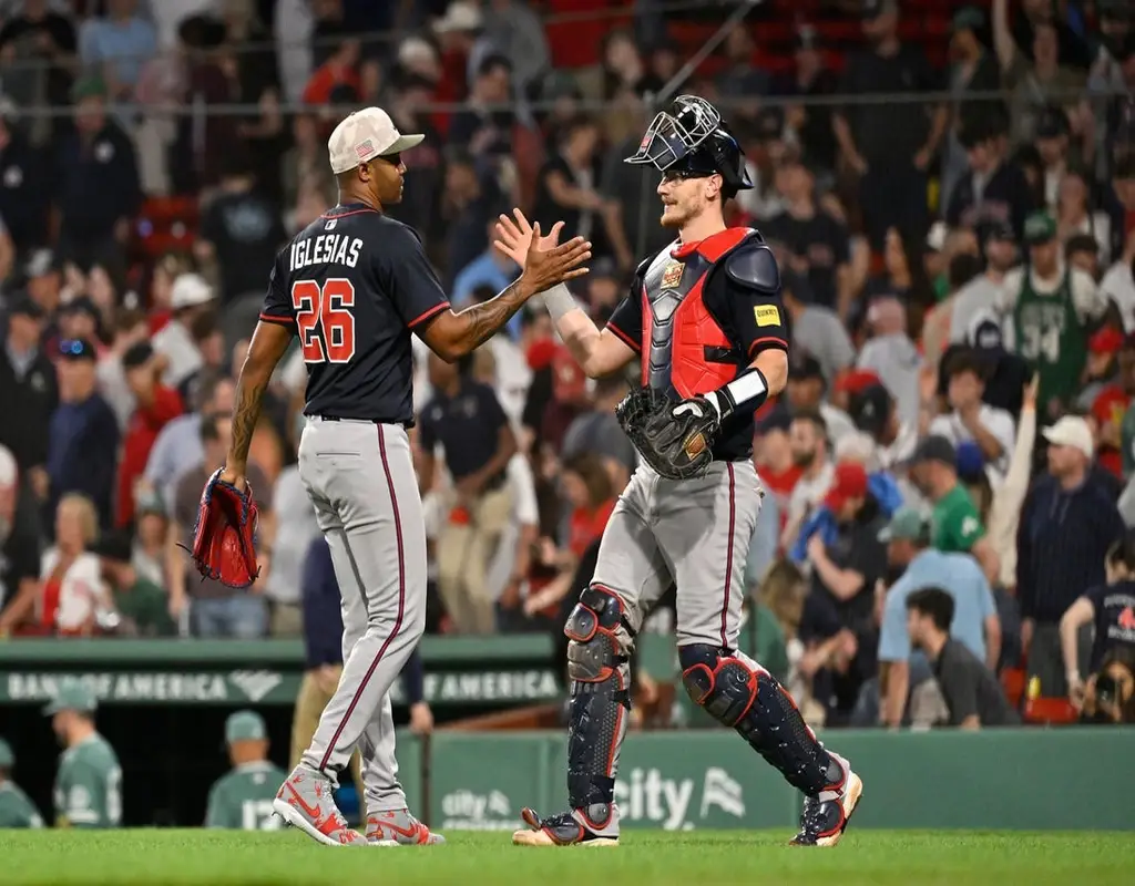 Boston Red Sox reliever #26 Iglesias and the catcher exchanging a high-five on the mound behind home plate in a packed stadium
