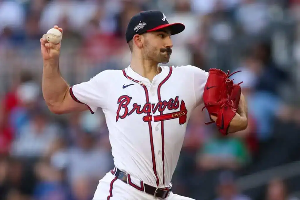 A baseball player in a grey Cardinals uniform celebrates enthusiastically, wearing a red helmet and gesturing in excitement on the field.