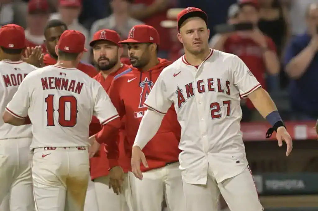 Los Angeles Angels players, including Mike Trout (27) and Kevin Newman (10), are gathered on the field during a game.