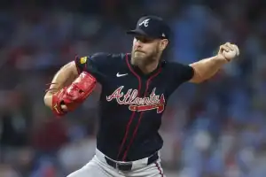 A pitcher in a dark blue Atlanta Braves jersey winds up to throw a baseball, showcasing focused determination on the mound.