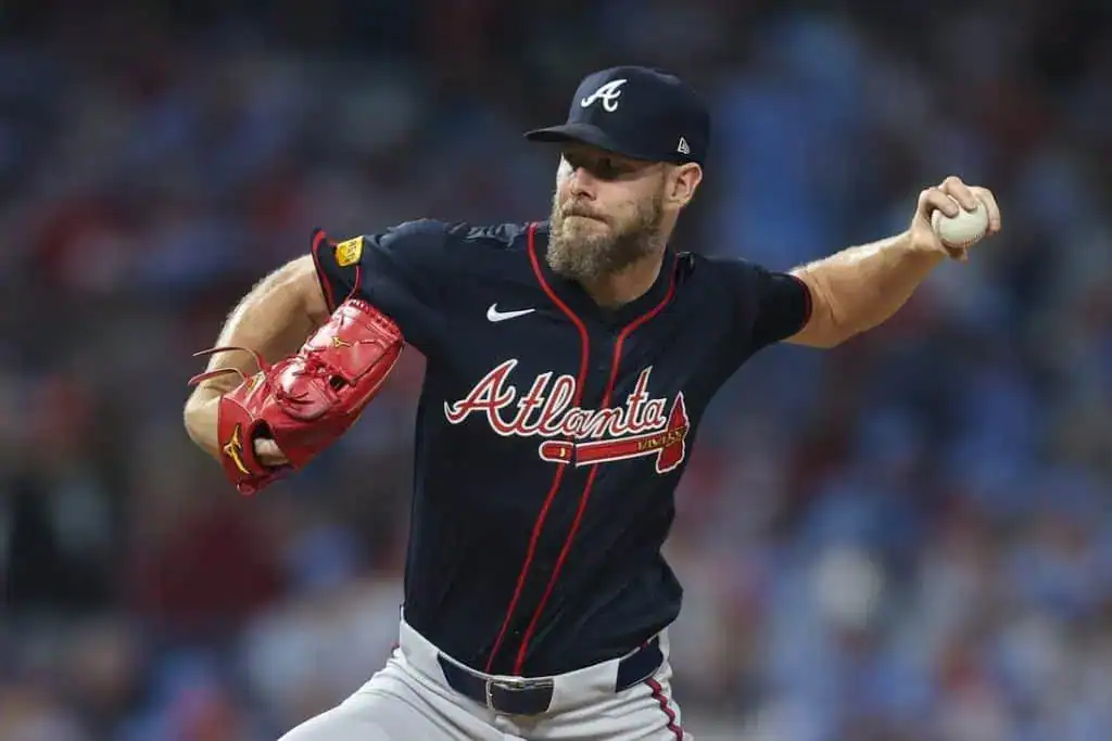5 A pitcher in a dark blue Atlanta Braves jersey winds up to throw a baseball, showcasing focused determination on the mound.