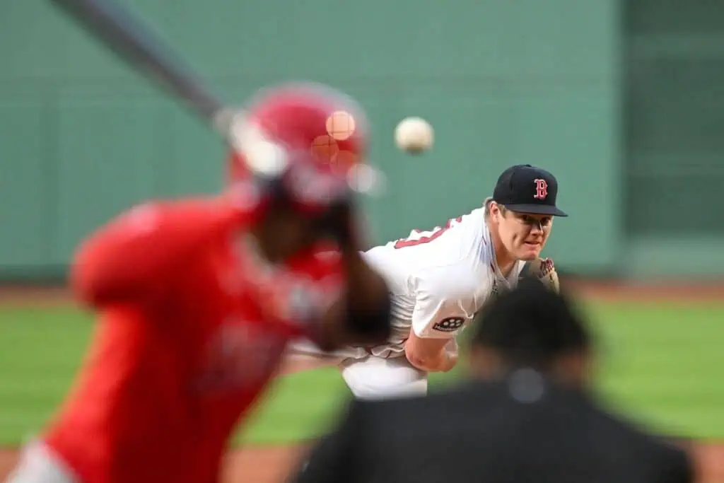 A pitcher throws a baseball towards a batter, who prepares to swing, as spectators watch from behind home plate.