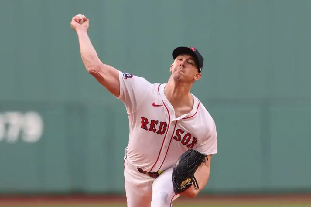 A pitcher in a red and white jersey with "RED SOX" throws a baseball, showcasing a powerful pitching motion on a field.