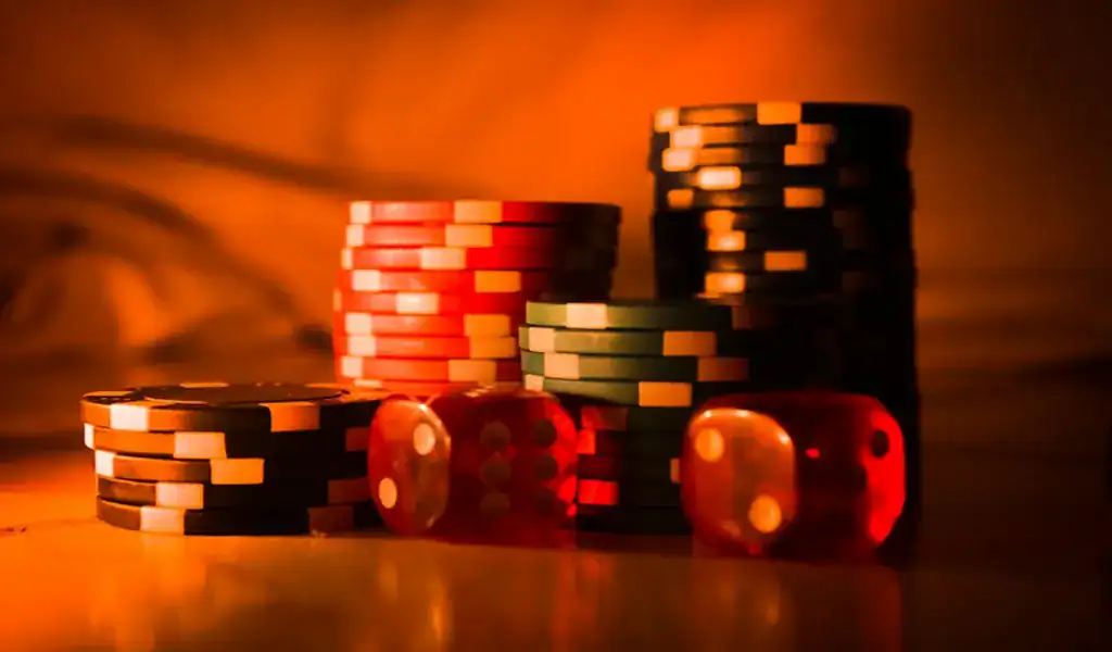 How To Get the Most Out of Your Betting Bonuses 3 Stacks of casino chips and red dice illuminated with warm orange lighting.