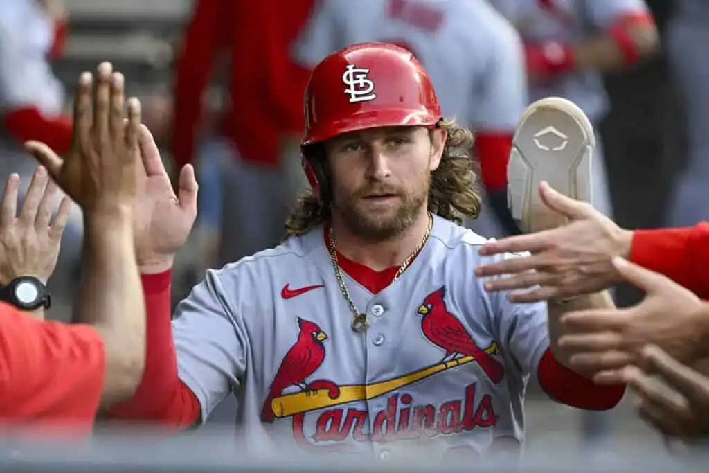 A baseball player in a Cardinals jersey celebrates with teammates, exchanging high-fives and cheers in a lively dugout setting.