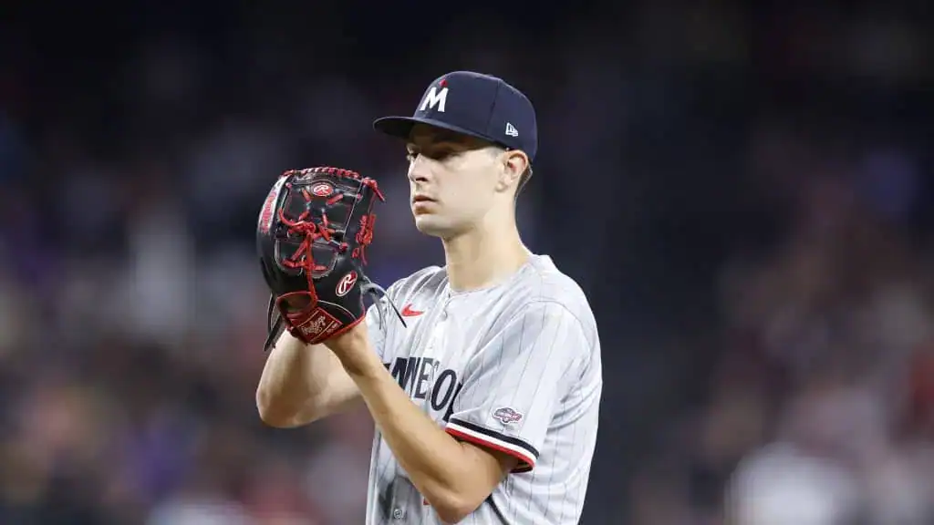 Oakland Athletics vs Minnesota Twins Picks and Predictions June 5th 2025 2 A baseball pitcher in a gray jersey prepares to throw a pitch, wearing a cap and a glove, with a blurred background of the stadium.
