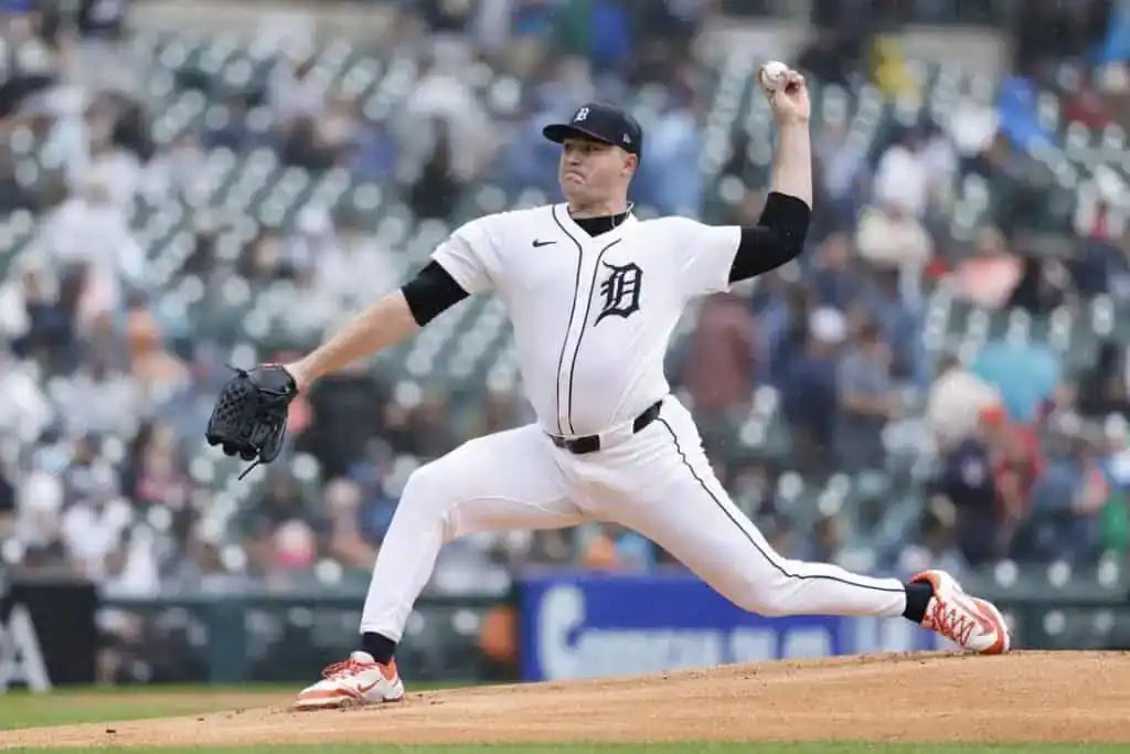 A Detroit Tigers pitcher in a white home uniform throws the ball from the pitcher's mound.