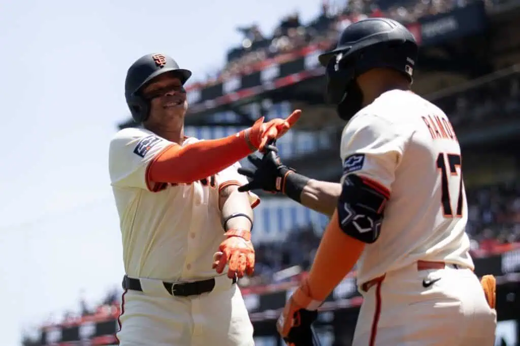 Two baseball players celebrate a successful play, wearing San Francisco Giants uniforms.
