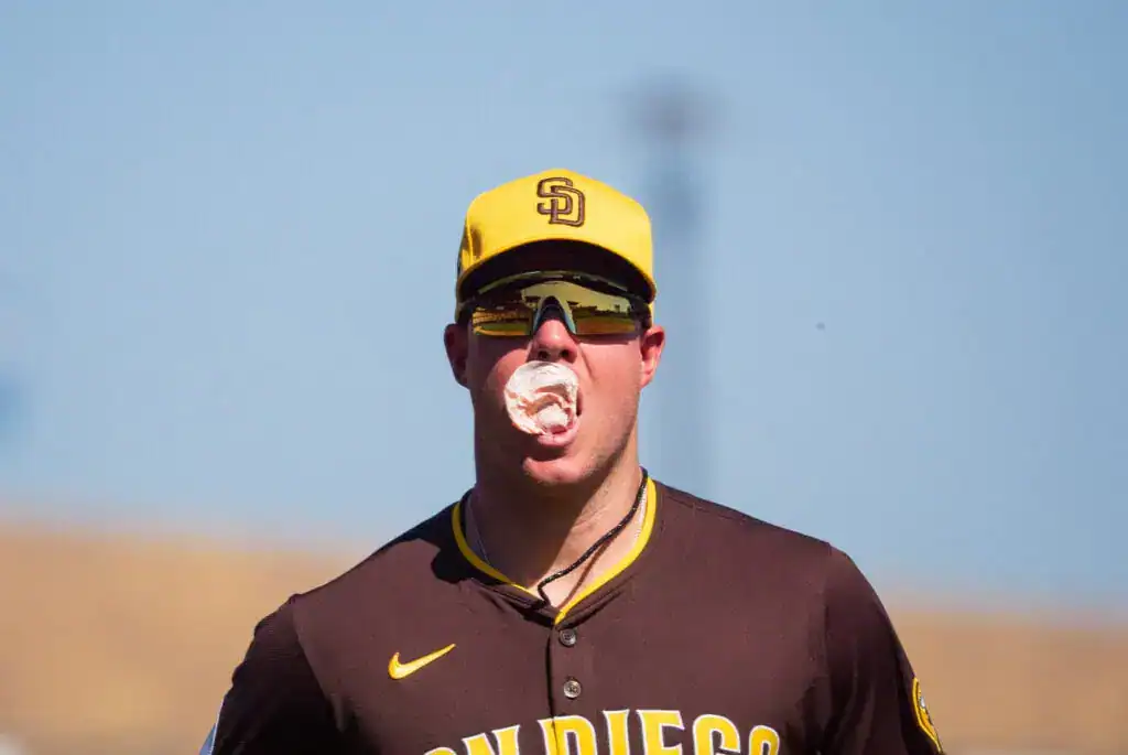 Cincinnati Reds vs San Diego Padres Picks and Predictions June 29th 2025 2 A close-up of San Diego Padres player Gavin Sheets wearing a team cap and sunglasses, with a large piece of bubblegum in his mouth.