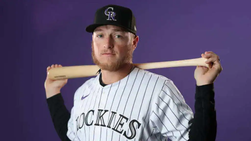 Colorado Rockies vs New York Mets Picks and Predictions June 6th 2025 2 A baseball player in a Colorado Rockies jersey poses confidently, holding a bat across his shoulders against a purple backdrop.