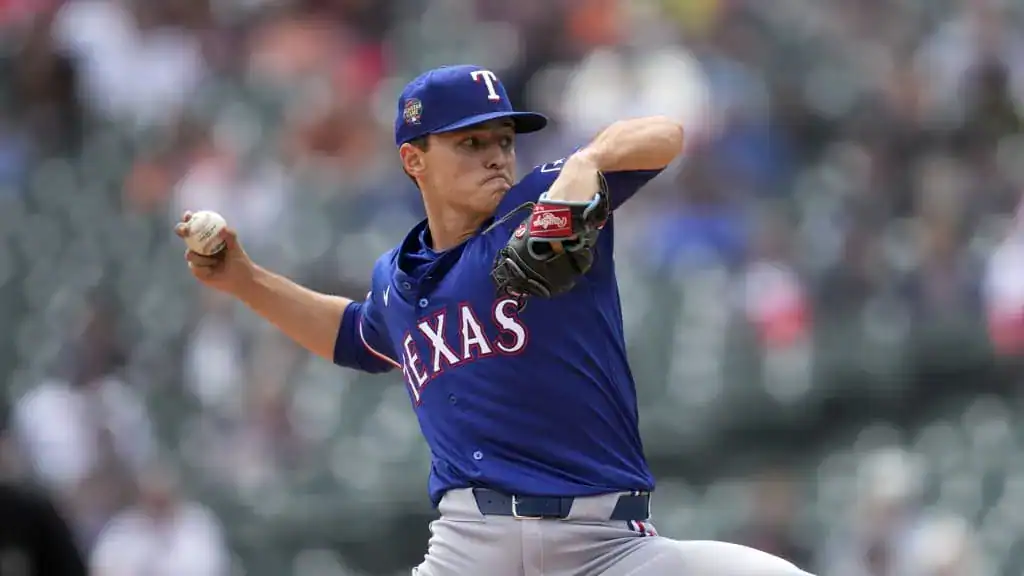 Texas Rangers vs Seattle Mariners Picks and Predictions June 29th 2025 2 A Texas Rangers pitcher in a blue jersey winds up to throw a baseball on a sunny day, surrounded by a cheering crowd in the background.