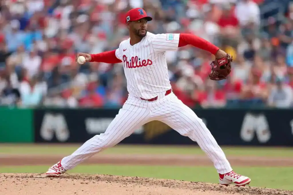 Pittsburgh Pirates vs Philadelphia Phillies Picks and Predictions June 6th 2025 2 A Philadelphia Phillies pitcher is in mid-delivery on the mound, wearing a red and white striped uniform, with fans in the background.
